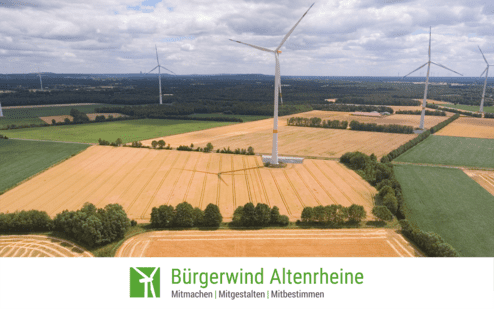 Luftaufnahme eines Feldes mit Windr&auml;dern im Hintergrund und einem Logo von B&uuml;rgerwind Altenreine am unteren Bildrand.