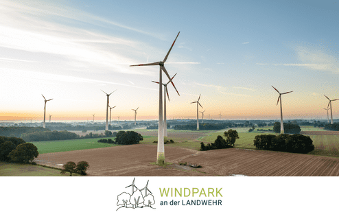Luftaufnahme eines Windparks mit mehreren Windturbinen in einer l&auml;ndlichen Landschaft bei Sonnenaufgang.