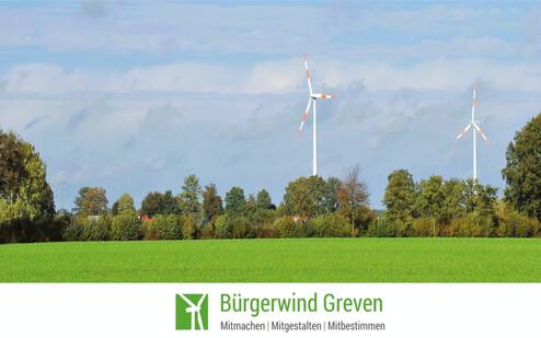 Zwei Windkraftanlagen stehen in einer gr&uuml;nen Landschaft unter einem blauen Himmel mit wenigen Wolken.